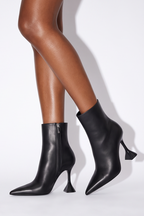 Pointed toe black ankle boots with a sculptural flared heel and side zip closure, made of smooth vegan PU leather.