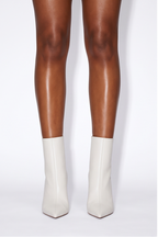 Pointed toe flared high heel ankle boots in clean off-white, featuring a sculptural heel and smooth vegan leather.