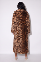A model viewed from behind wearing a long leopard-print faux fur coat, paired with beige high heels, against a plain white studio background.