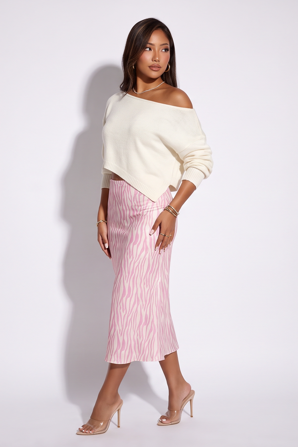 Dusty pink zebra print satin midi skirt with a bias cut, paired with a light off-shoulder sweater and clear heels.